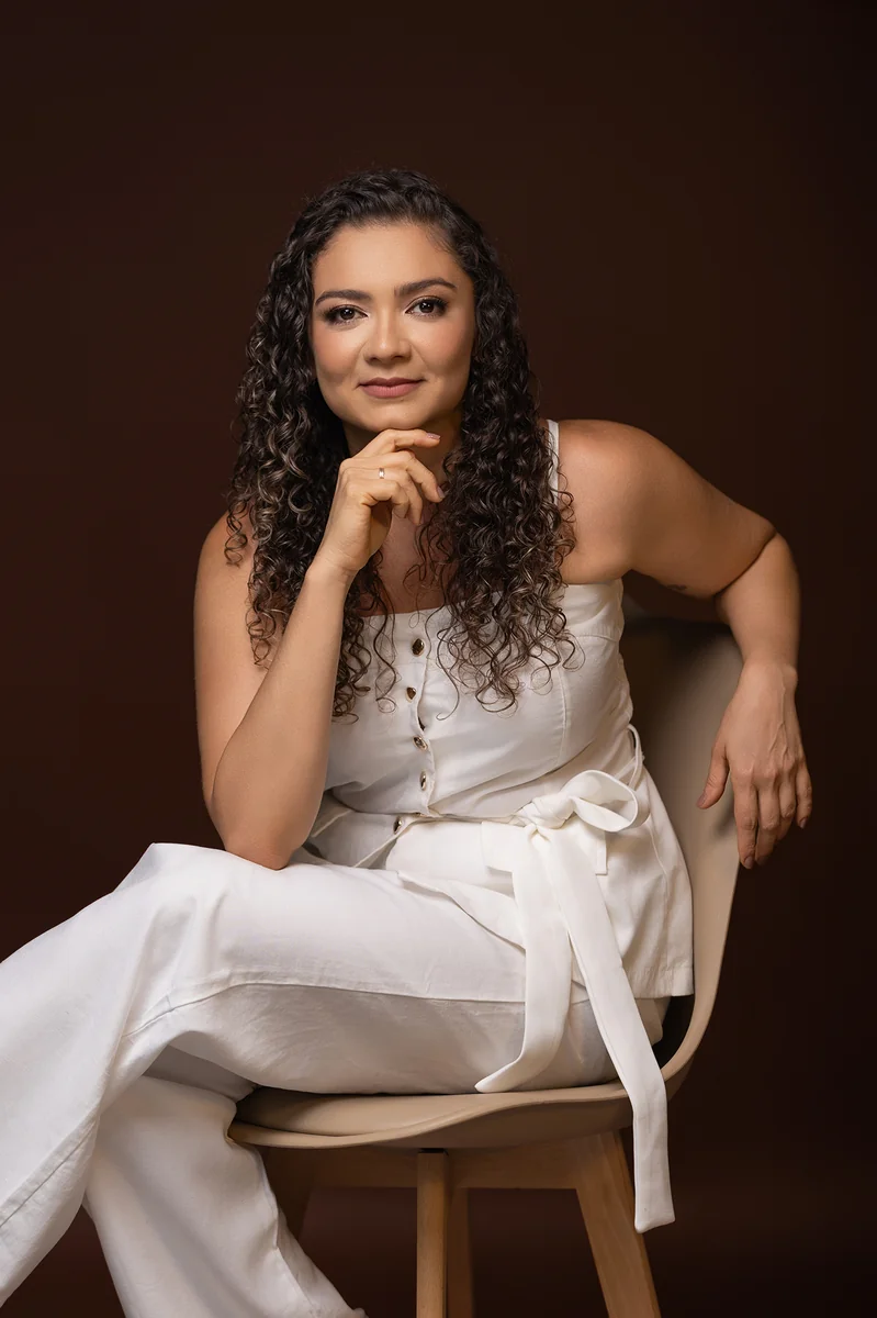 Juliana Marques sentada na poltrona, vestida de branco